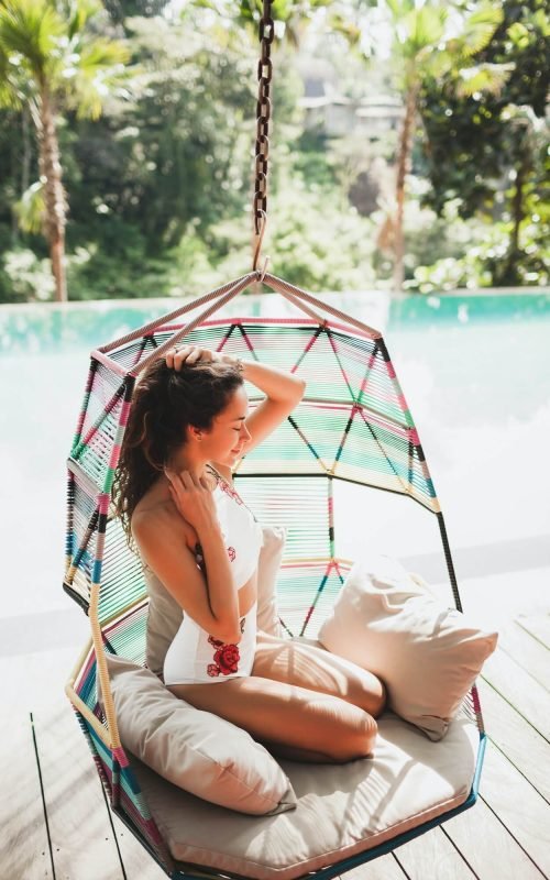 woman-in-white-swimsuit-enjoying-in-hanging-chair-swing-on-poolside-in-luxury-hotel-1-1.jpg